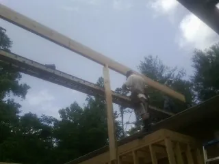 Carpenter setting a ridge beam over a new addition frame — Ice Dam Removal by Roofing Brothers in Meredith