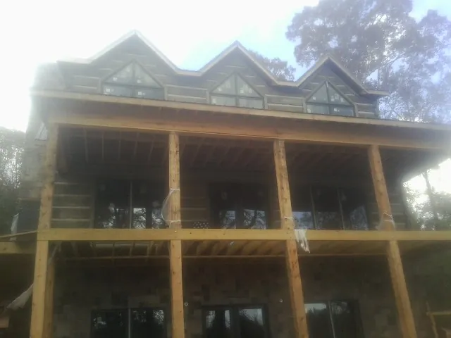Dormers and porch framing on a large log home under construction — Roof Coating work by our crew in Meredith