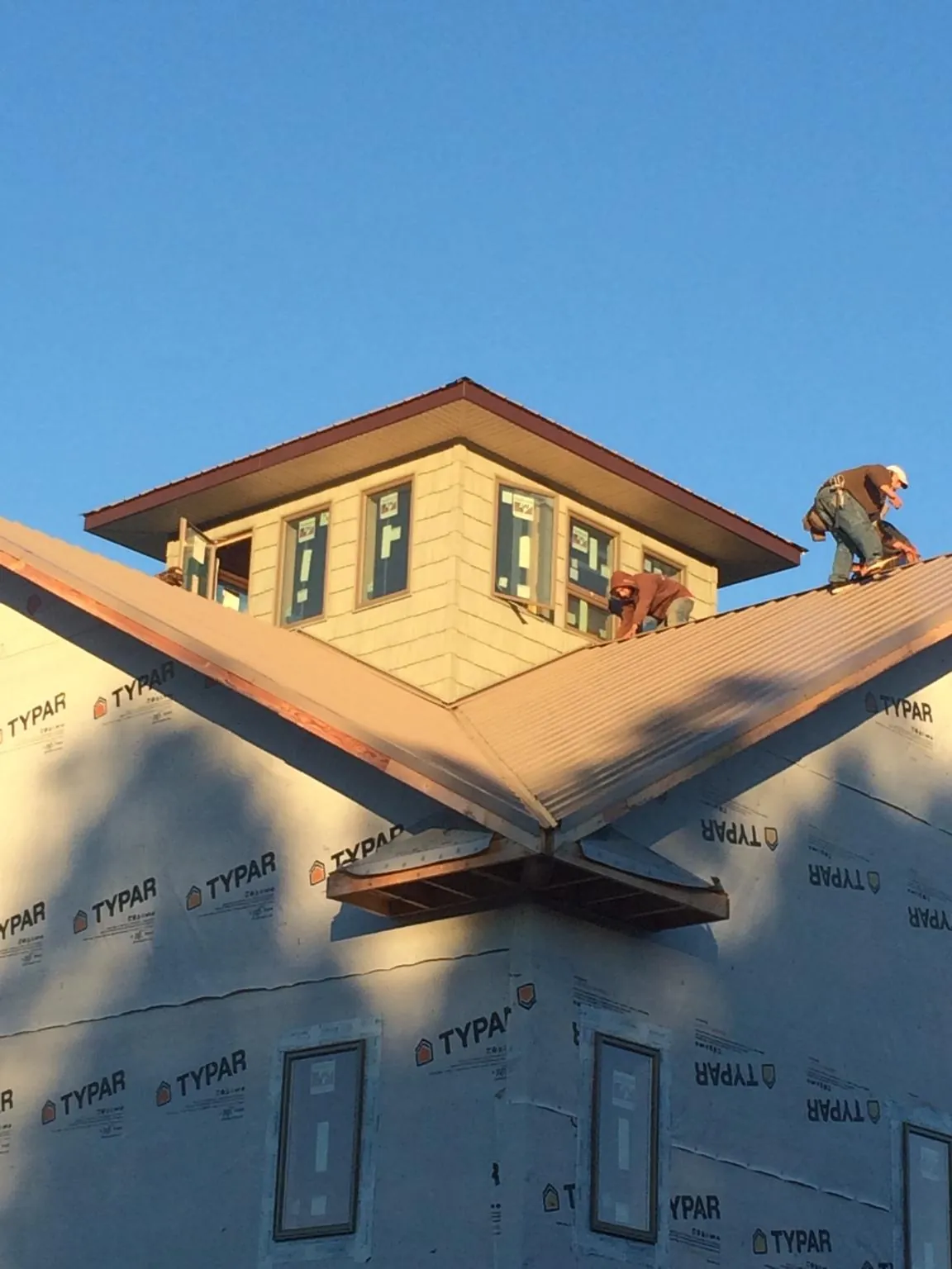 Roofers working around a rooftop cupola on a new metal roof at sunset — Roof Waterproofing in Meredith by Roofing Brothers
